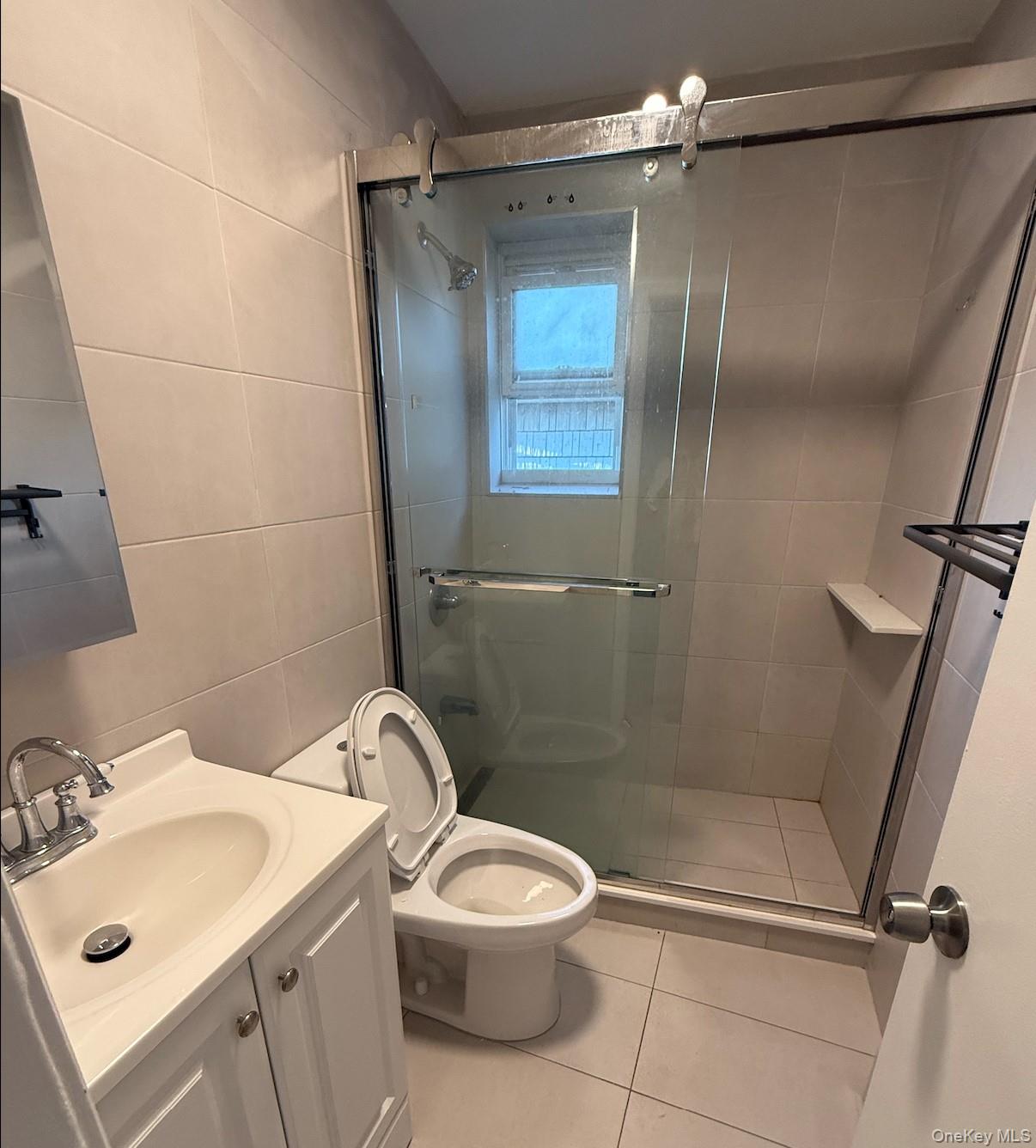 43-24 163rd Street Queens, NY 11358 - Photo 5 of 12 Full bathroom with vanity, a shower stall, light tile patterned floors, and tile walls