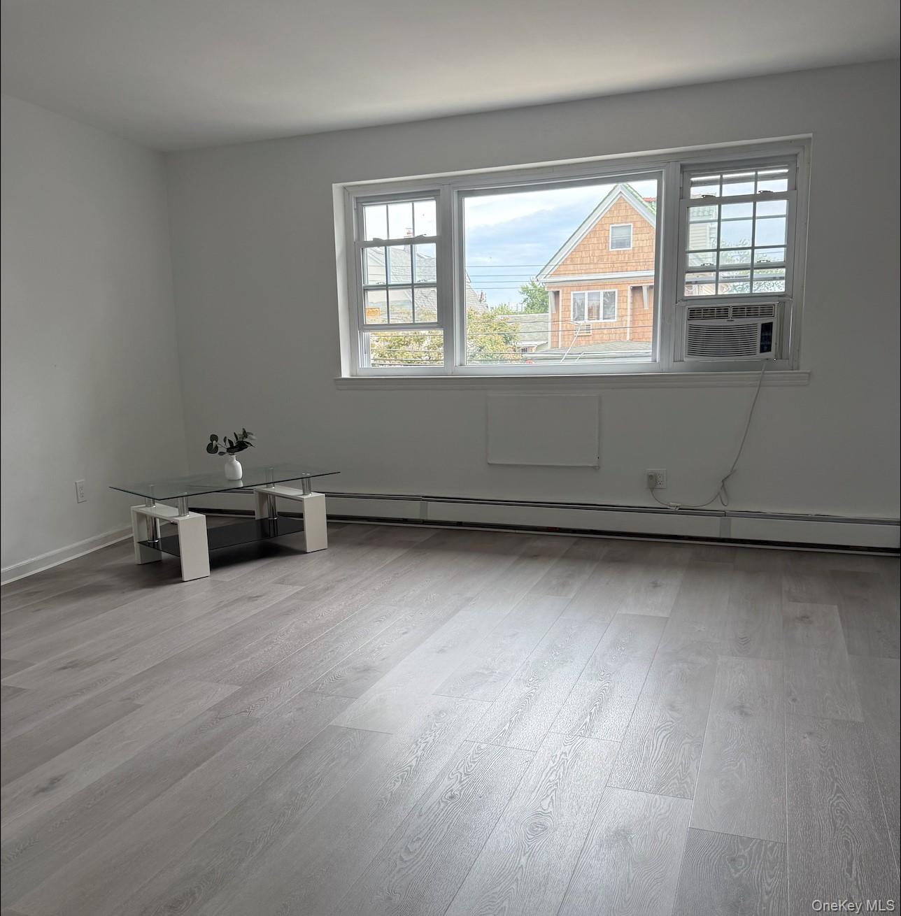 43-24 163rd Street Queens, NY 11358 - Photo 9 of 12 Spare room featuring healthy amount of natural light, light wood finished floors, a baseboard radiator, and cooling unit