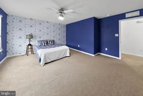 a view of a livingroom with a ceiling fan & windows