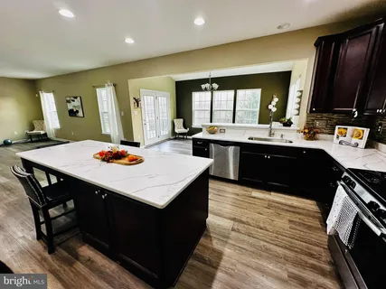 a kitchen with stainless steel appliances kitchen island granite countertop a table chairs sink and cabinets