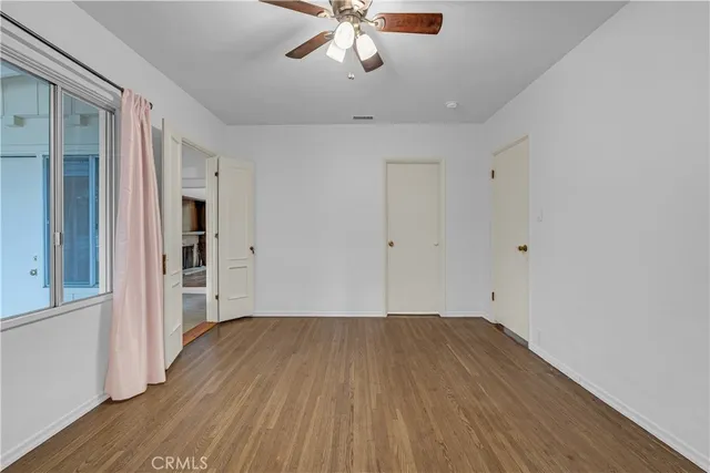 a view of a room with wooden floor a ceiling fan and windows