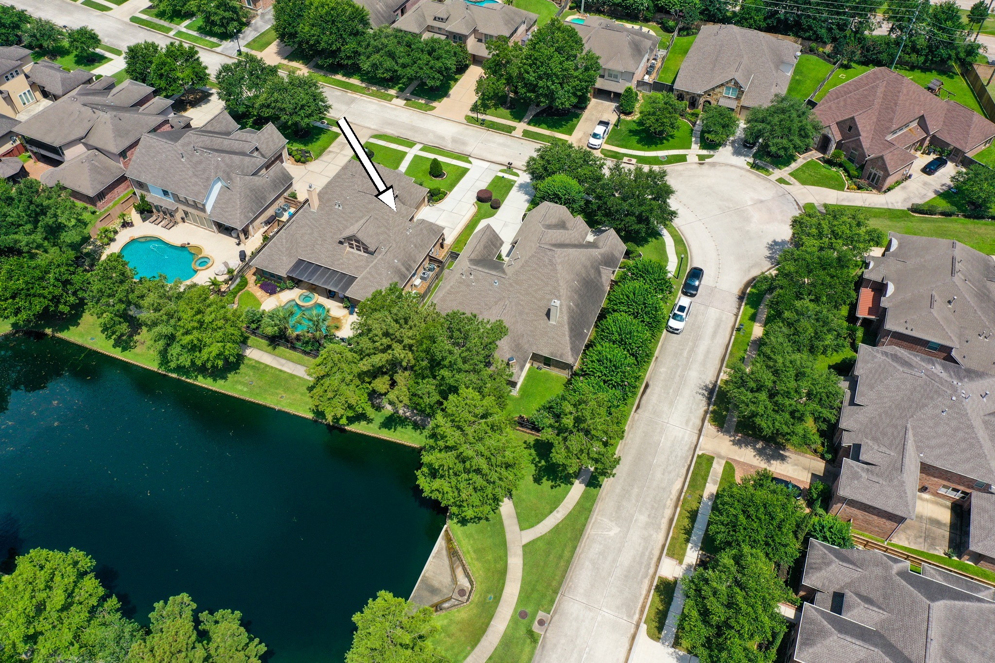 2407 Hendricks Lakes Drive Spring, TX 77388 - Photo 2 of 50 From above, the home’s water-front setting comes into focus with the walking path, water, neighboring outdoor spaces, and pool/spa all visible. Behind the home, the covered outdoor living area and backyard overlook the water-view backdrop, creating an easy connection to the lake-centered lifestyle of Lakes of Cypress Forest.