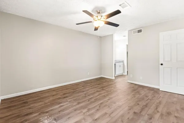 an empty room with wooden floor and a ceiling fan