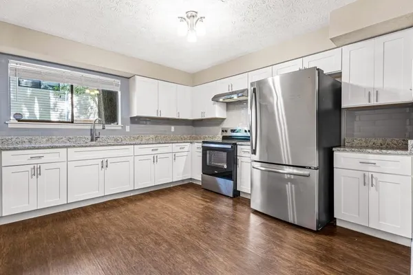 a kitchen with granite countertop white cabinets and white stainless steel appliances
