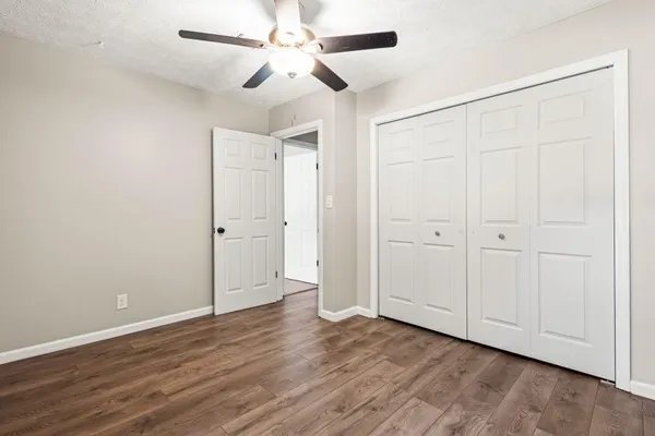 an empty room with wooden floor closet fan and windows