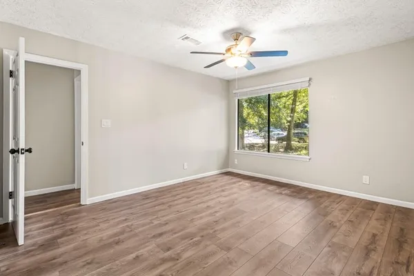 a view of an empty room with wooden floor and a window