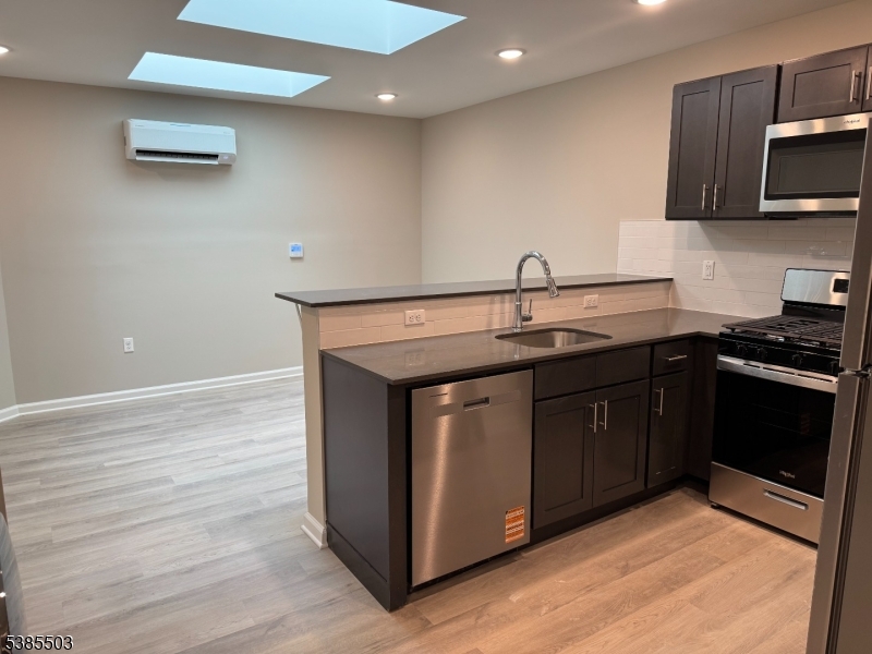 10 East Washington Avenue, Unit 302 Washington, NJ 07882 - Photo 3 of 4 a kitchen with stainless steel appliances granite countertop a sink and a stove top oven with wooden floor