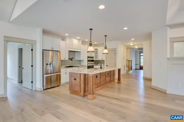 a large kitchen with stainless steel appliances kitchen island white cabinets and wooden floors