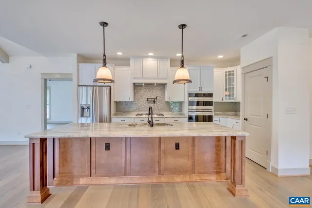 a kitchen with kitchen island granite countertop a sink a counter space appliances and cabinets