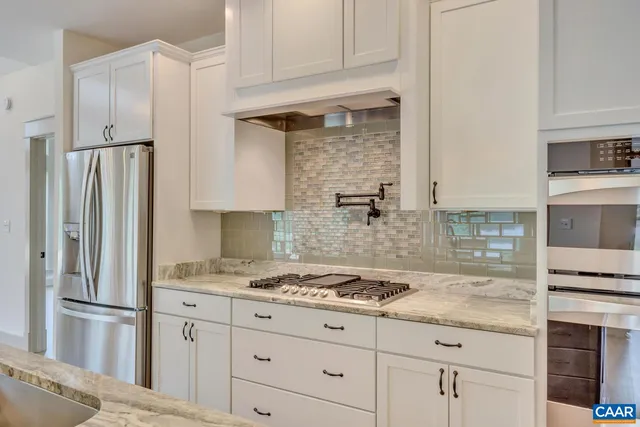a kitchen with granite countertop a refrigerator and a stove top oven