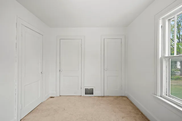 a view of an empty room with window and mirror