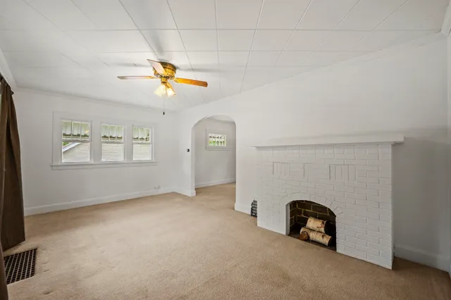 an empty room with windows and ceiling fan