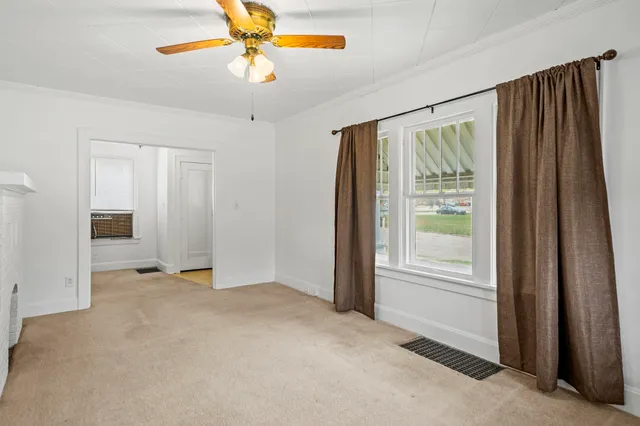a view of an empty room with chandelier fan and a window