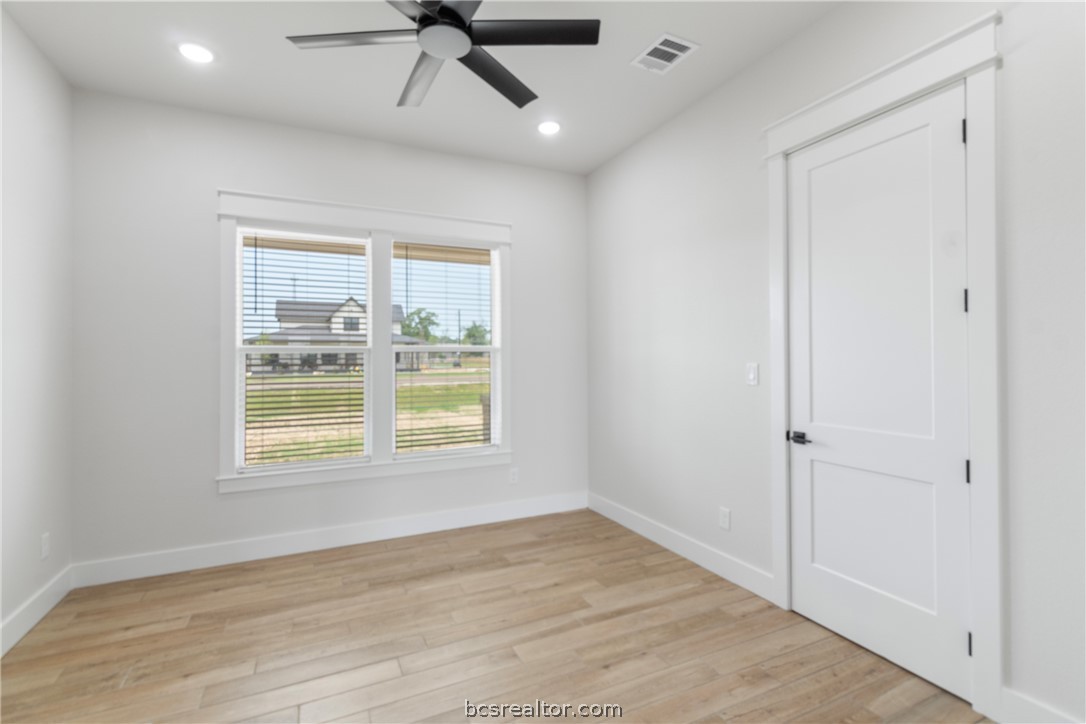 7822 Mathis Crk Drive Bryan, TX 77808 - Photo 33 of 43 an empty room with wooden floor ceiling fan and windows