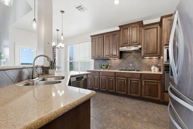 a kitchen with stainless steel appliances granite countertop a sink a stove and a refrigerator