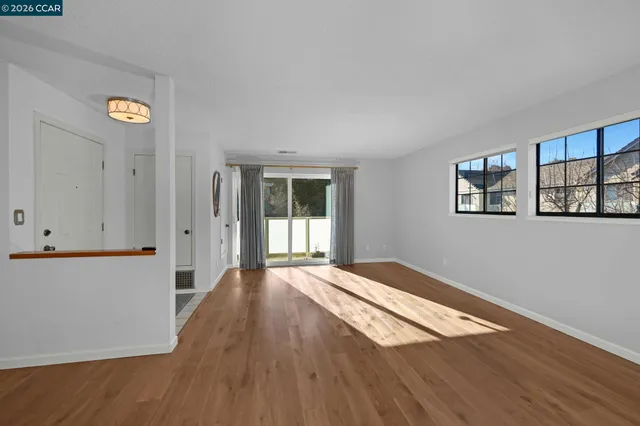 a view of an empty room with window and wooden floor