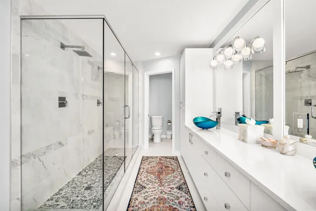 a large white kitchen with sink and view of living room