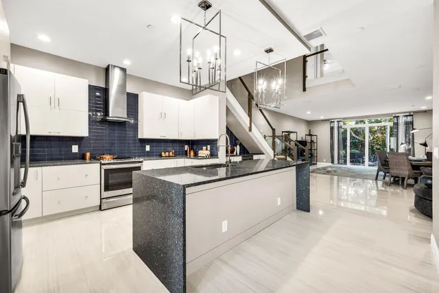 a large kitchen with stainless steel appliances kitchen island granite countertop a stove and a sink