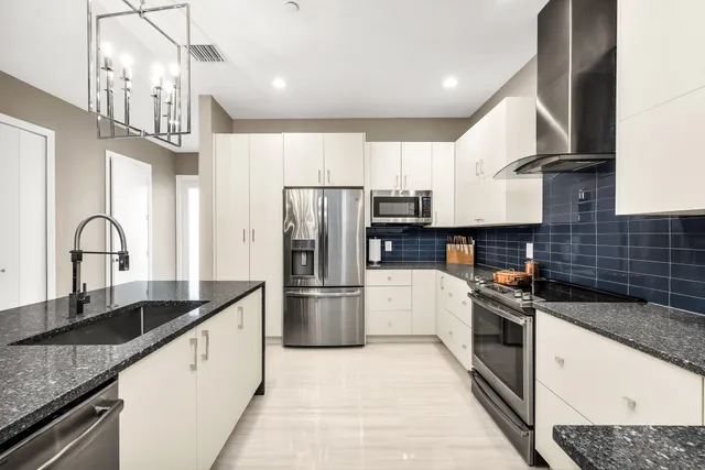 a kitchen with kitchen island granite countertop a sink stainless steel appliances and cabinets