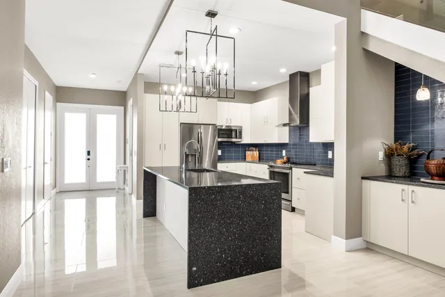 a kitchen with stainless steel appliances granite countertop a refrigerator a sink dishwasher a stove and a dining table with wooden floor