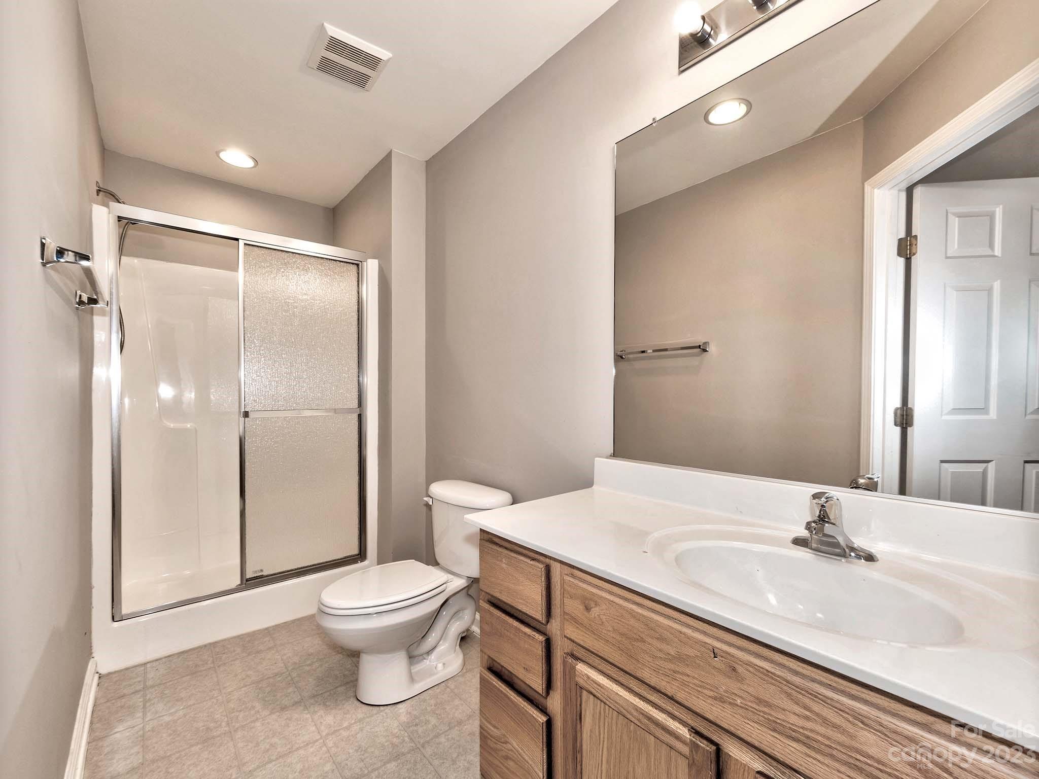 4849 Prosperity Ridge Road Charlotte, NC 28269 - Photo 26 of 40 a bathroom with a granite countertop sink toilet a large mirror a glass door shower and a mirror