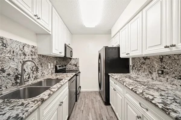 a kitchen with stainless steel appliances granite countertop a sink stove and refrigerator