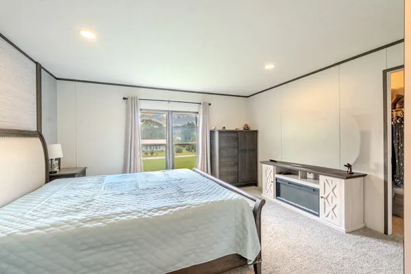a bedroom with a large bed and a flat tv screen on dresser