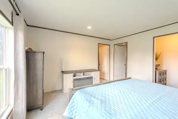 a bedroom with a bed and a flat tv screen on dresser