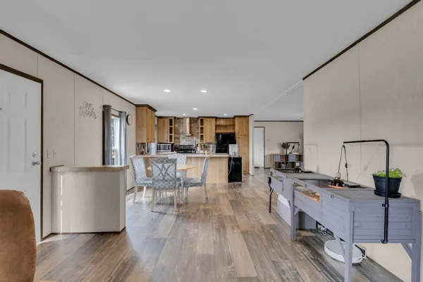 a living room with stainless steel appliances granite countertop furniture wooden floor and a kitchen view