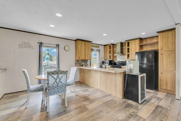 a kitchen with stainless steel appliances granite countertop a refrigerator a stove a sink a dining table and chairs with wooden floor