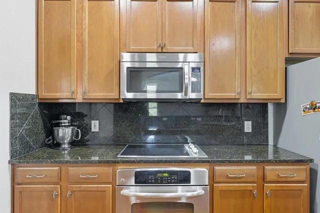a kitchen with granite countertop white cabinets and stainless steel appliances