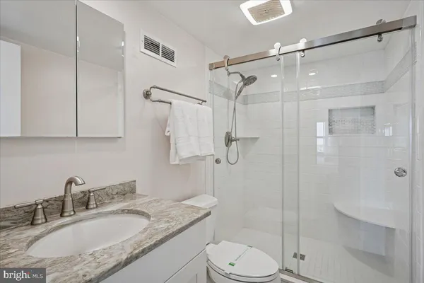 a bathroom with a granite countertop sink toilet and shower