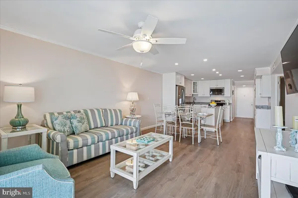a living room with furniture kitchen view and a wooden floor