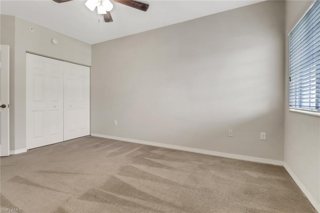 20160 Estero Gardens Circle, Unit 202 Estero, FL 33928 - Photo 20 of 44 an empty room with a chandelier fan and windows