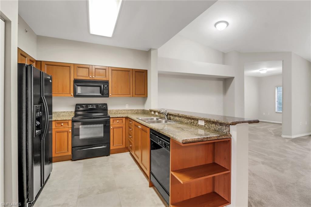 20160 Estero Gardens Circle, Unit 202 Estero, FL 33928 - Photo 5 of 44 a kitchen with stainless steel appliances granite countertop a stove top oven a sink and a refrigerator