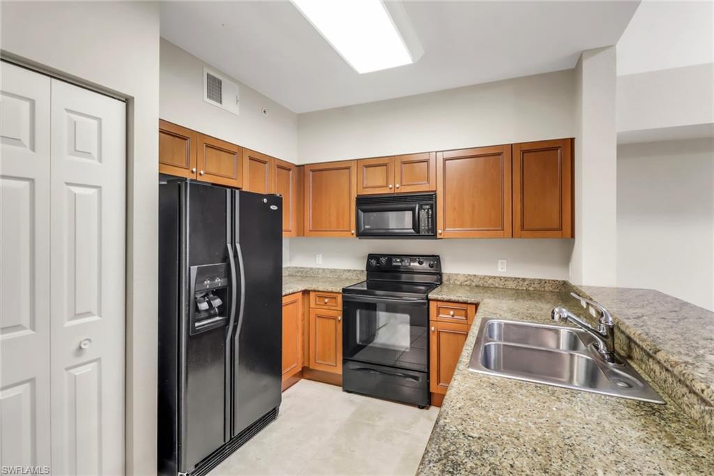 20160 Estero Gardens Circle, Unit 202 Estero, FL 33928 - Photo 6 of 44 a kitchen with stainless steel appliances granite countertop a refrigerator stove and sink