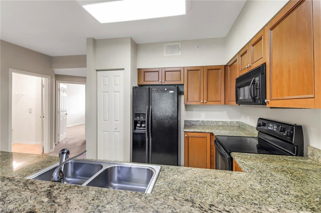 20160 Estero Gardens Circle, Unit 202 Estero, FL 33928 - Photo 7 of 44 a kitchen with stainless steel appliances granite countertop a refrigerator a stove top oven and a sink
