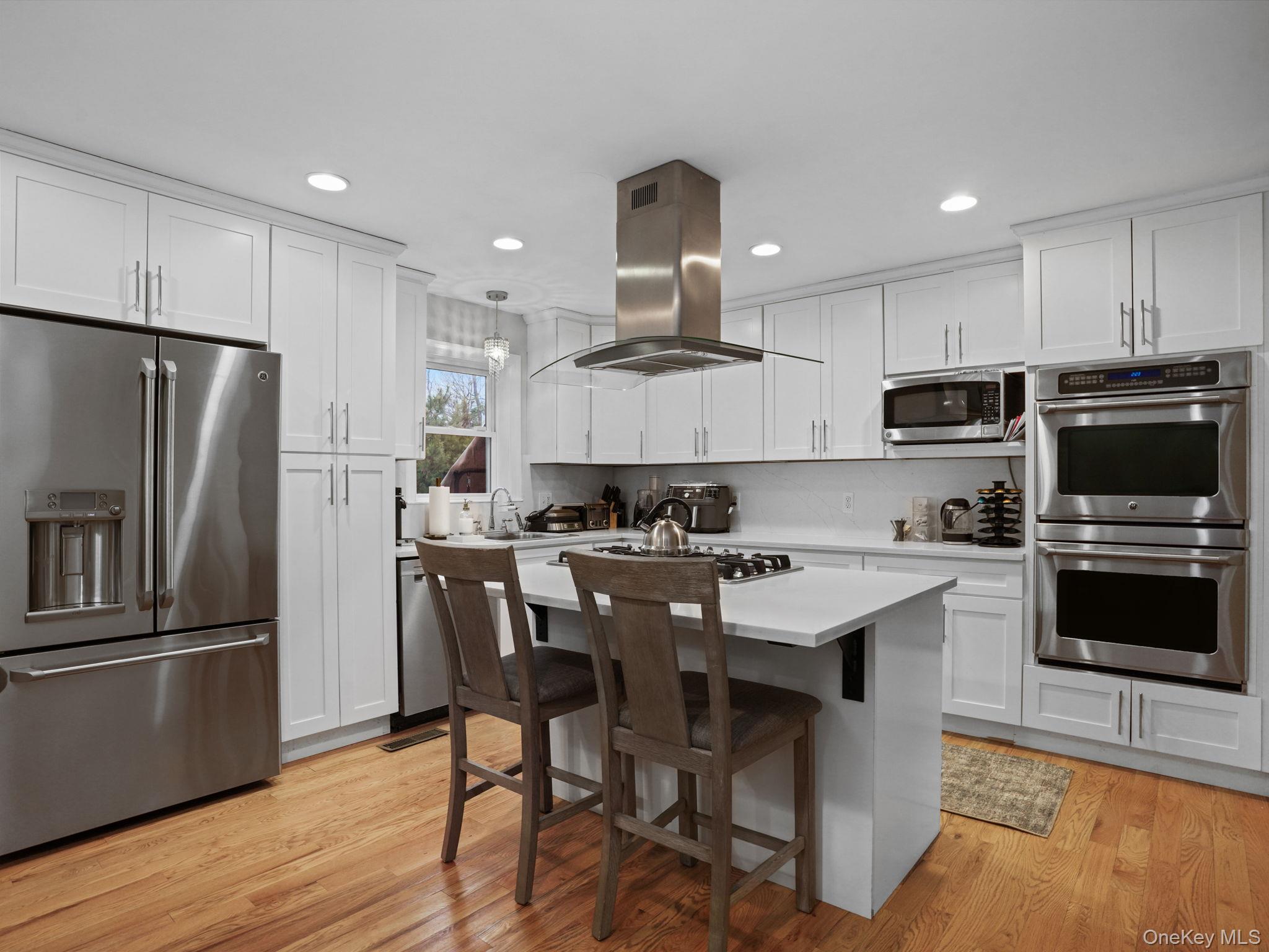 38 Kathwood Road White Plains, NY 10607 - Photo 14 of 44 Kitchen with appliances with stainless steel finishes, white cabinets, a breakfast bar, island range hood, and a center island
