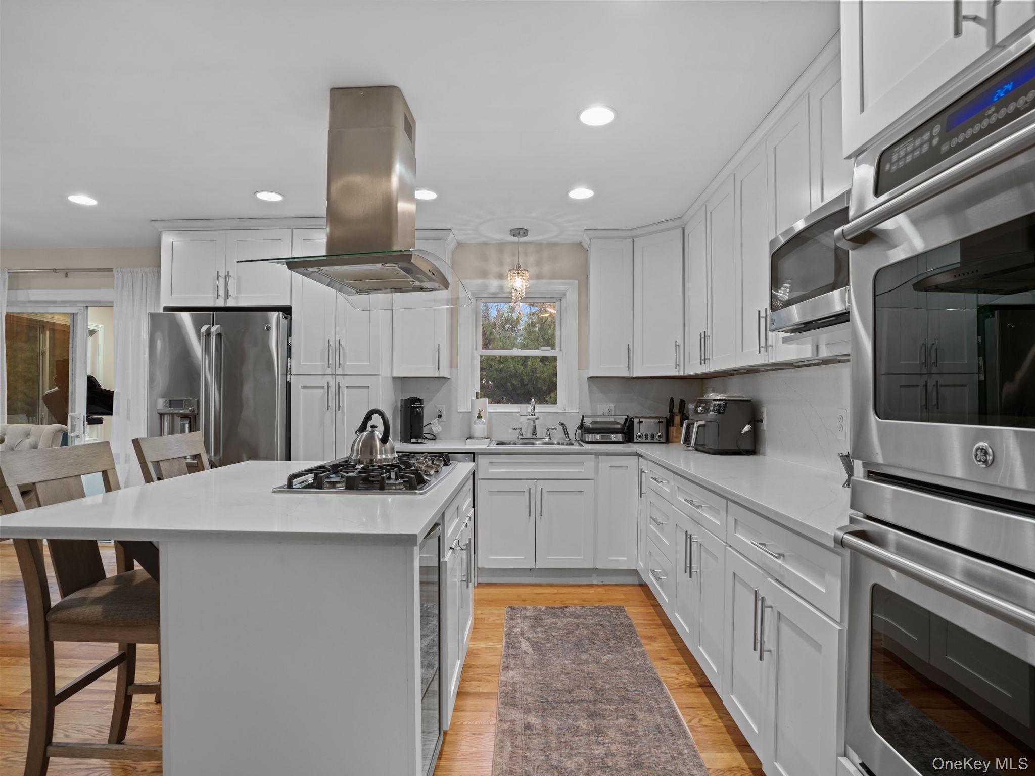 38 Kathwood Road White Plains, NY 10607 - Photo 16 of 44 Kitchen with appliances with stainless steel finishes, a kitchen bar, white cabinetry, light wood finished floors, and recessed lighting