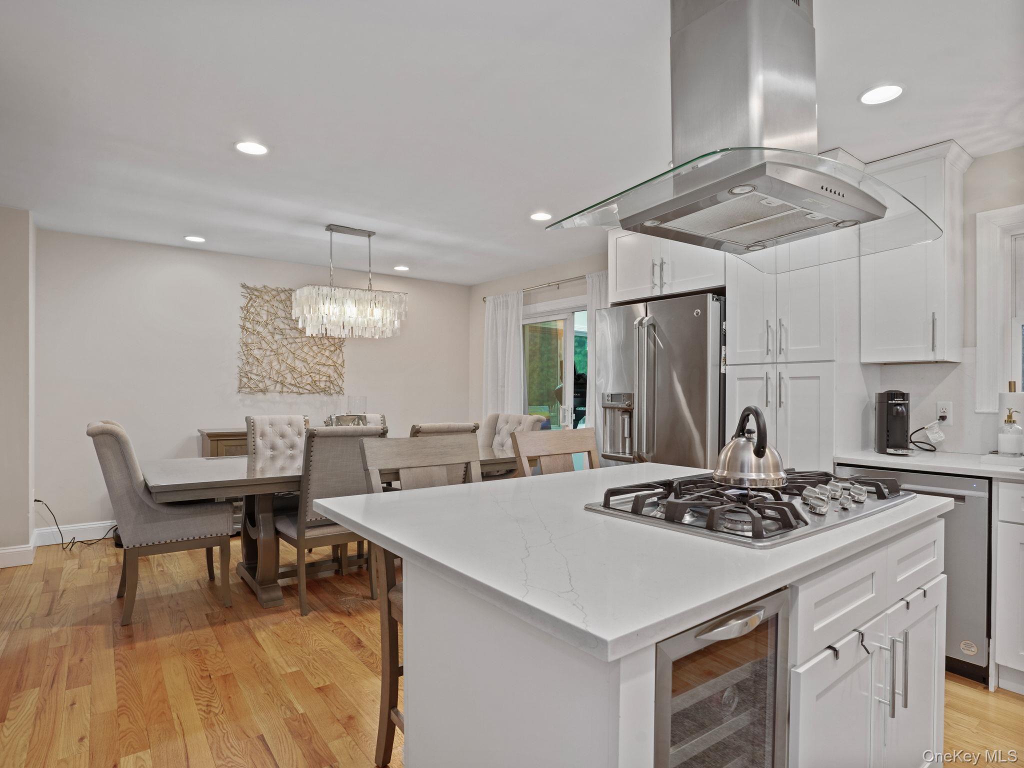 38 Kathwood Road White Plains, NY 10607 - Photo 17 of 44 Kitchen with white cabinets, wine cooler, a breakfast bar area, light wood-style flooring, and island exhaust hood