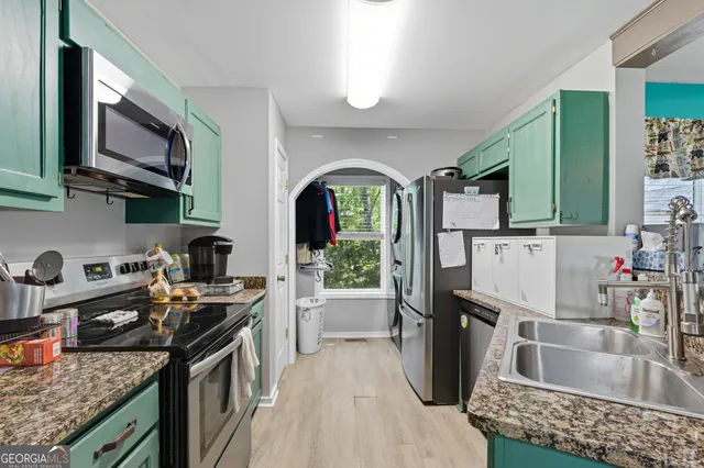 a kitchen with granite countertop a stove a sink and a microwave