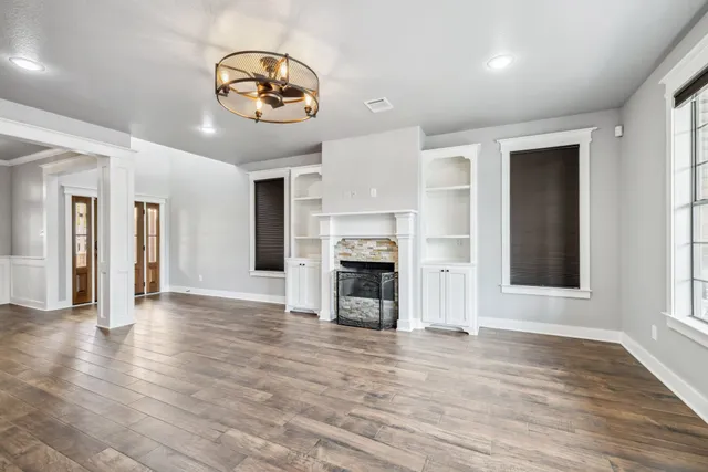 an empty room with wooden floor a fireplace and window