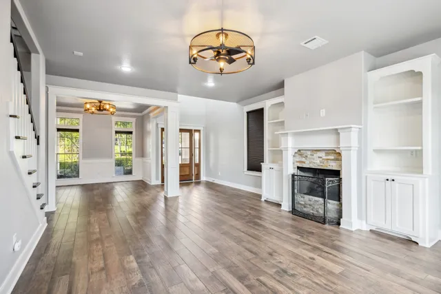 an empty room with wooden floor a fireplace and window
