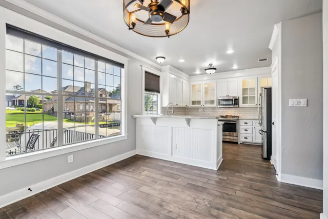 a kitchen with stainless steel appliances granite countertop a stove a sink and a refrigerator with wooden floors