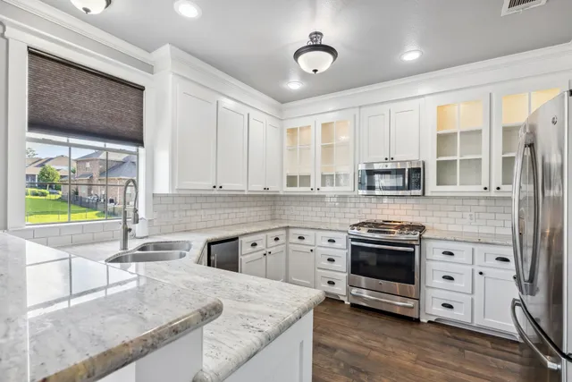 a kitchen with stainless steel appliances granite countertop a stove a sink and a microwave