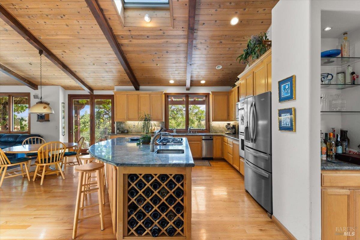 13404 Flora Ranch Road Healdsburg, CA 95448 - Photo 28 of 66 a kitchen with stainless steel appliances kitchen island granite countertop a refrigerator a stove and a dining table with wooden floor