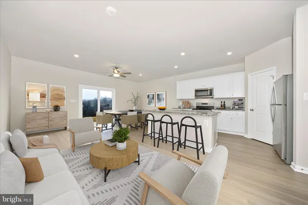 a living room with furniture kitchen area and a wooden floor