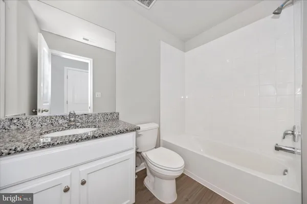a bathroom with a granite countertop sink a toilet and bathtub