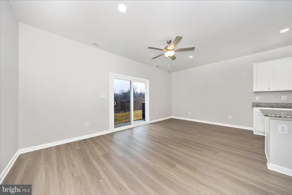 a view of an empty room with a kitchen and wooden floor