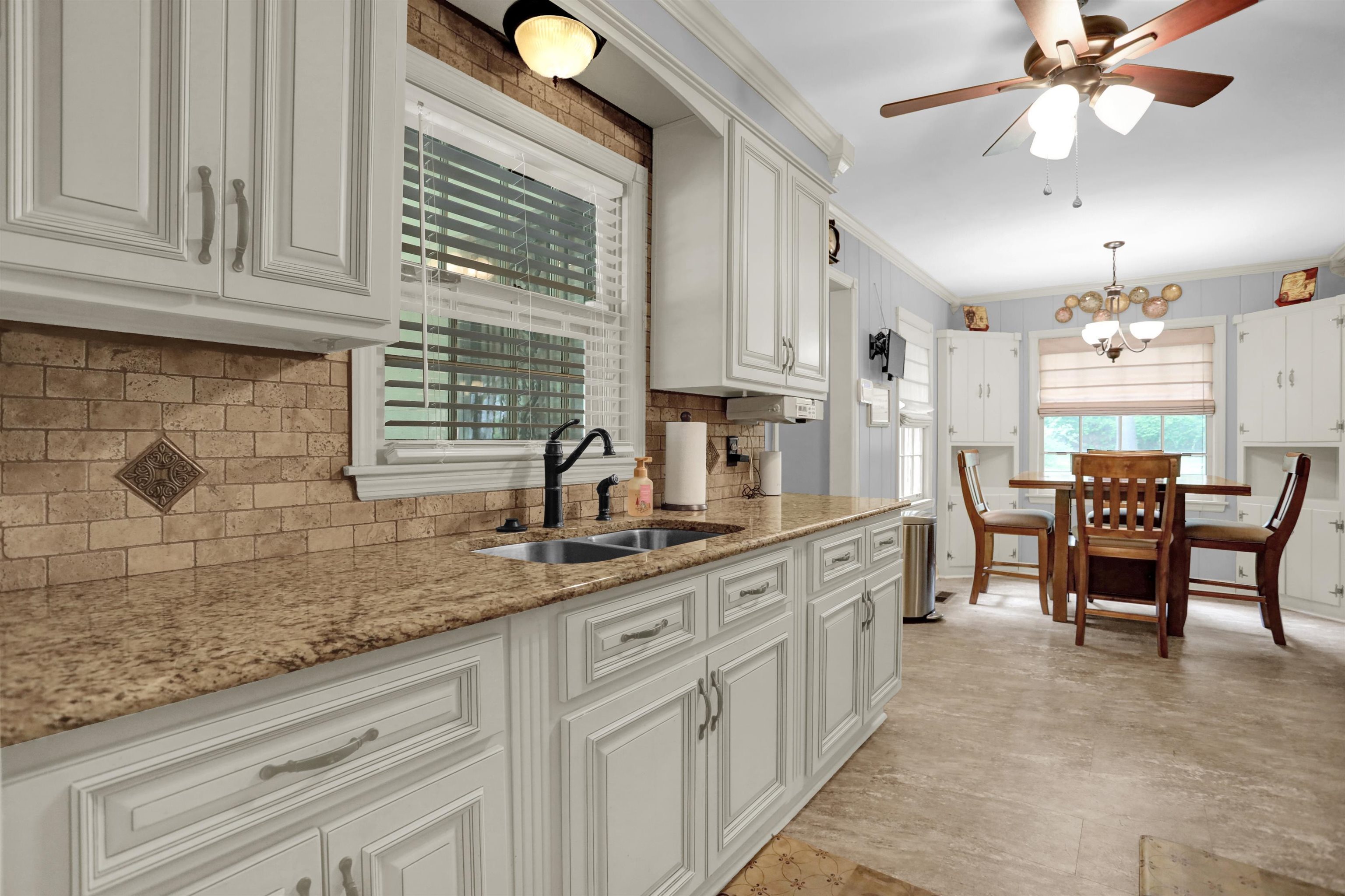 1277 Old Hickory Road Memphis, TN 38116 - Photo 4 of 29 Kitchen featuring decorative backsplash, white cabinetry, light stone counters, a sink, and ceiling fan with notable chandelier